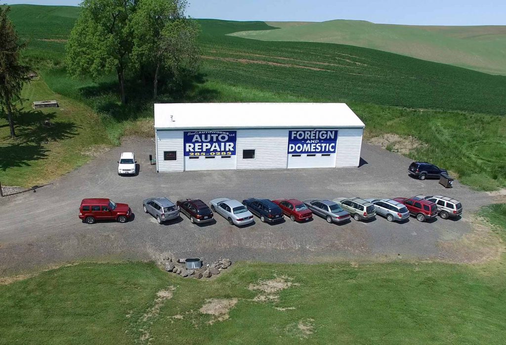 Exterior of Brent's Autoworks shop with cars and green hills